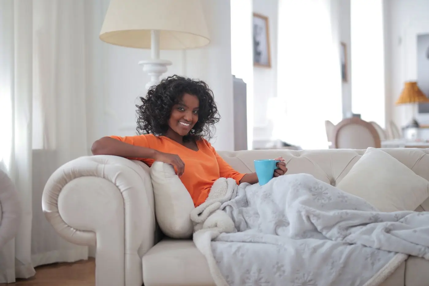 Mulher relaxando com uma xícara em um sofá limpo, seco e cheiroso na sala de casa