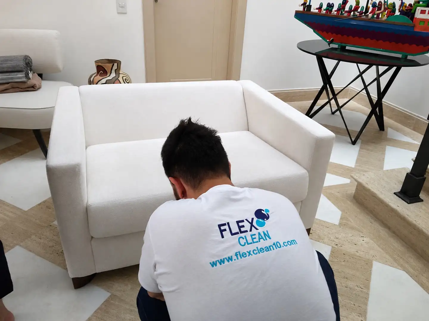 Profissional da Flex Clean higienizando sofá branco na casa do cliente